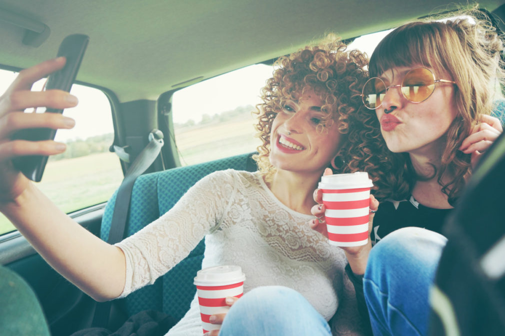 Dos chicas viajando juntas y haciéndose fotos con su teléfono móvil