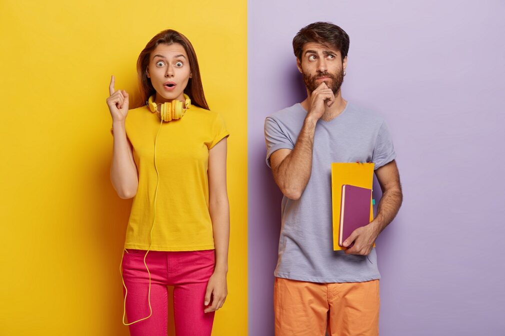 Thoughtful young European man holds chin, holds notebook and textbook, thinks about creative lesson, impressed woman in casual wear, points index finger up, gets unexpected idea in mind, isolated