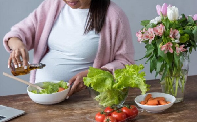 Una mujer embarazada aliña con aceite de oliva una ensalada, en imagen de recurso - Fundación Descubre