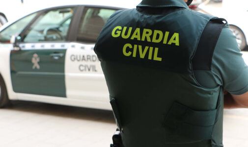 Agente de Guardia Civil junto a un coche oficial