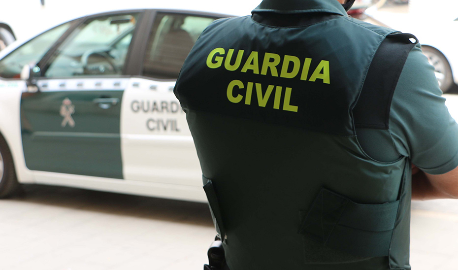 Agente de Guardia Civil junto a un coche oficial